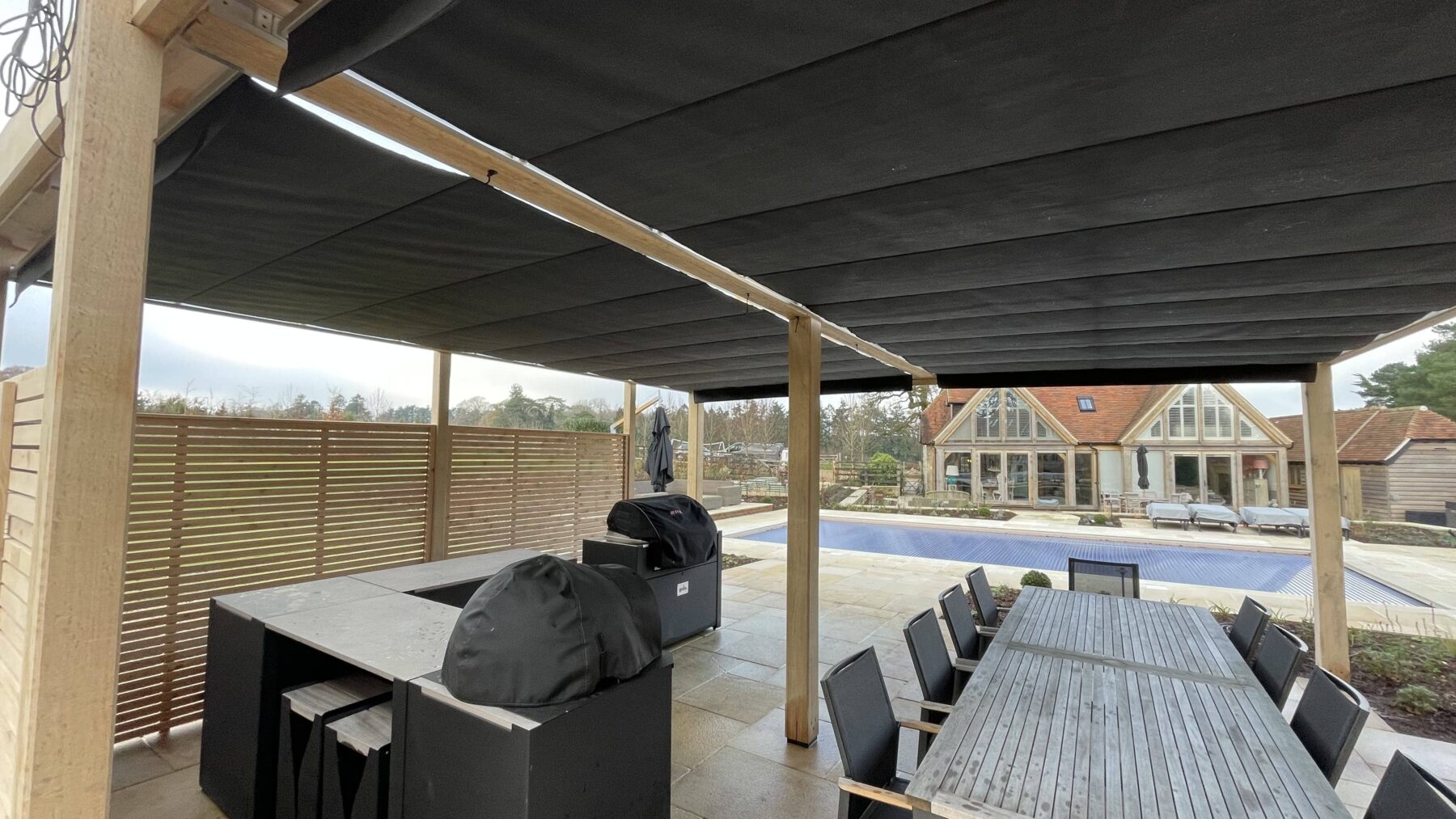 Oak pergola with retractable canopy shade and outdoor kitchen